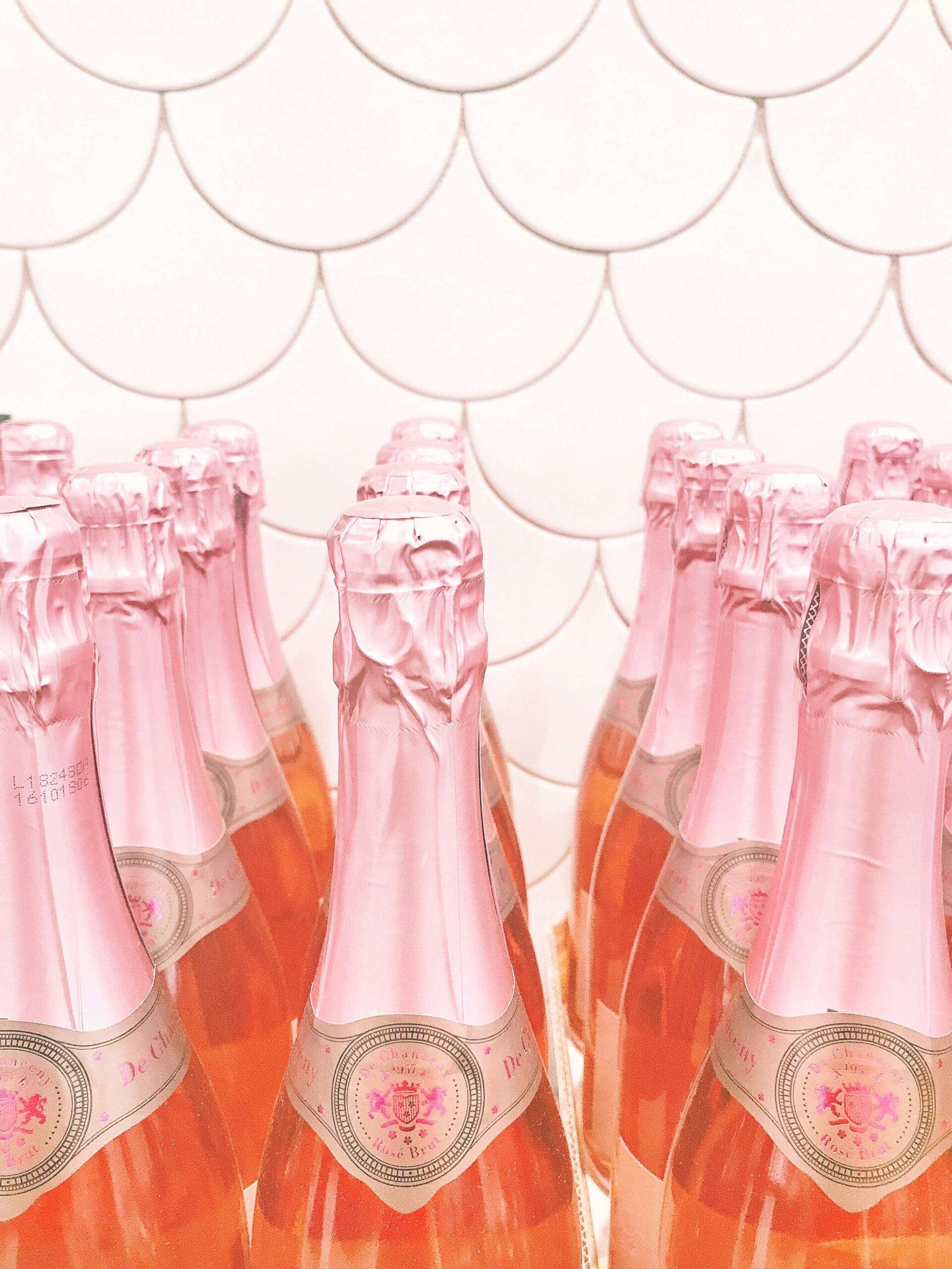 rows_of_pink_champagne_bottles_arranged_closely_together_against_a_white_scalloped_tile_background_creating_a_celebratory_and_feminine_aesthetic_-laura_keenan-nervous_system_coach